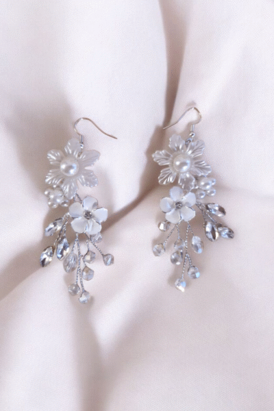 Les boucles Clarté d’Argent jouent sur la lumière et la transparence. Leur design floral délicatement argenté, paré de cristaux, ajoute une note de fraîcheur à toute tenue de mariée. Détails : Matière : fil argenté, perles nacrées, cristaux Longueur : env. 7 cm