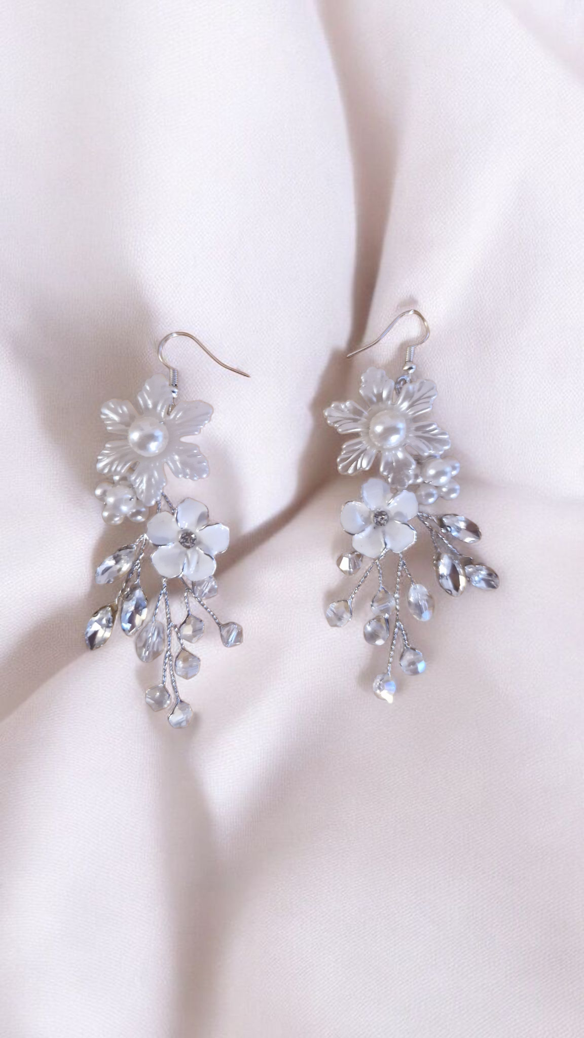 20250516 133836 (1) Les boucles Clarté d’Argent jouent sur la lumière et la transparence. Leur design floral délicatement argenté, paré de cristaux, ajoute une note de fraîcheur à toute tenue de mariée. Détails : Matière : fil argenté, perles nacrées, cristaux Longueur : env. 7 cm